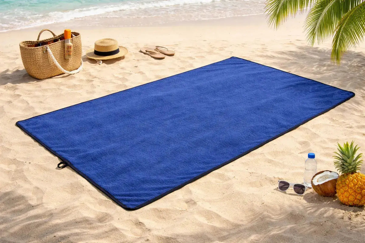 Premium strandhanddukar för solsäng och strand Navy 230x135 cm på stranden med sand och palmer.