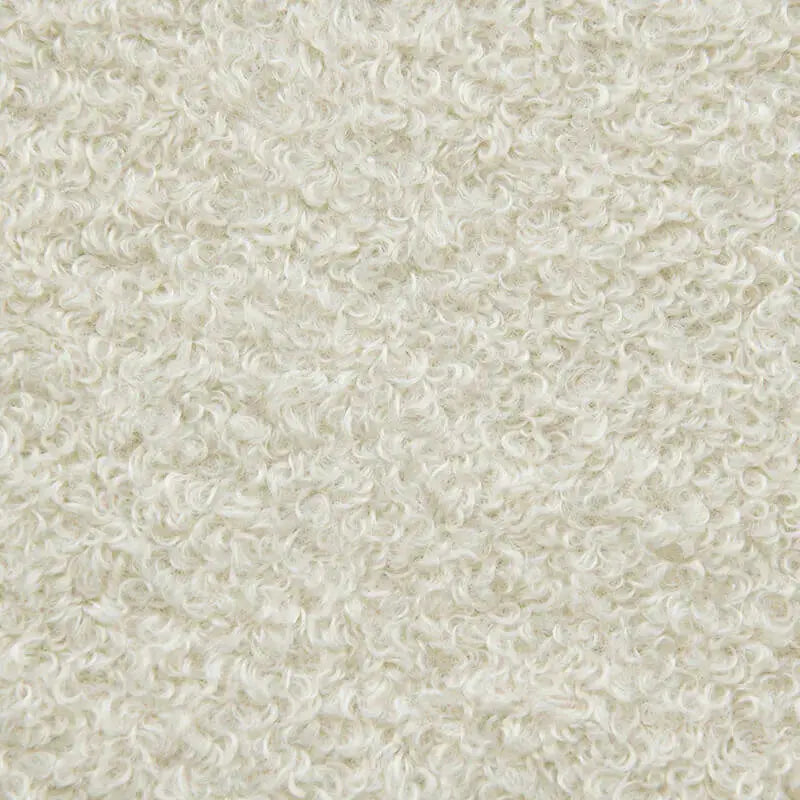 Närbild på mjukt, krämvitt teddytyg med lockig textur, perfekt för en fåtölj.